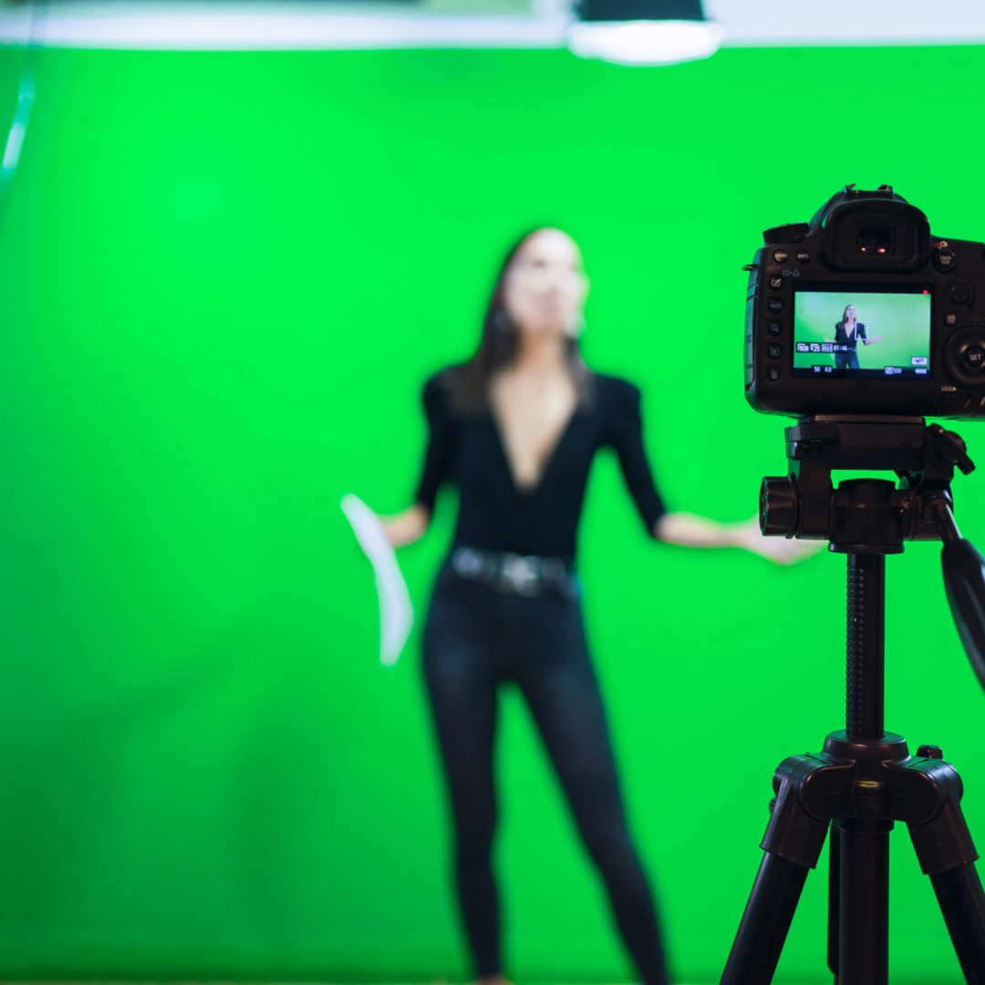 Full body of female host reading news on paper document while recording program for social media against chromakey screen